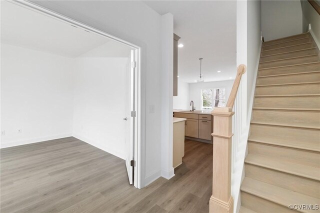 stairs featuring hardwood / wood-style flooring and sink