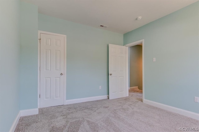 unfurnished bedroom with light colored carpet and a closet