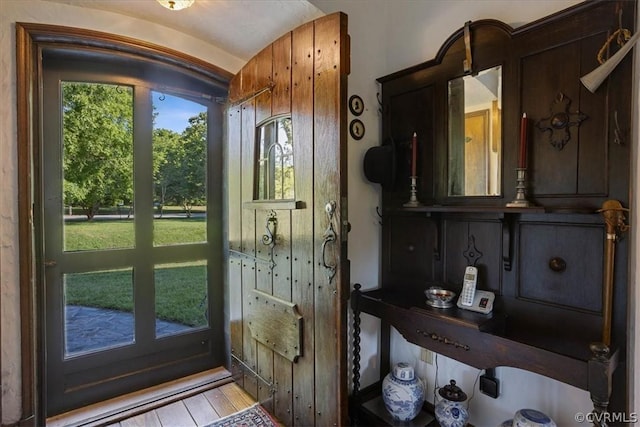 doorway to outside with light wood-type flooring and lofted ceiling