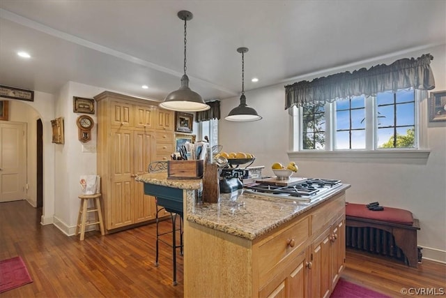 kitchen featuring dark wood-type flooring, light stone countertops, hanging light fixtures, a center island, and a breakfast bar area