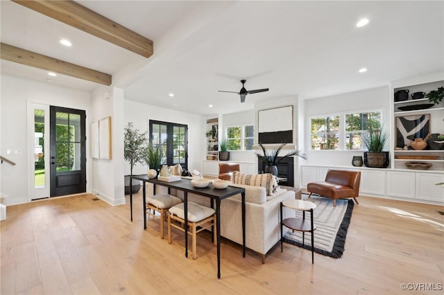 living room featuring beamed ceiling, ceiling fan, light wood-type flooring, and french doors