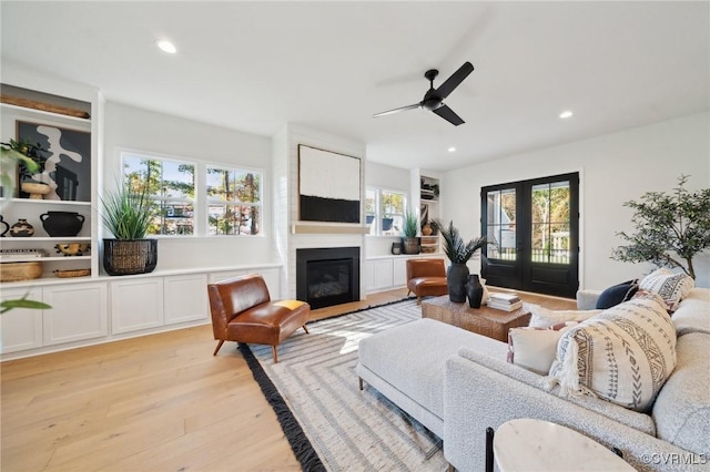 living room with french doors, plenty of natural light, a fireplace, and light wood-type flooring