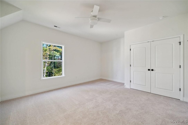 unfurnished bedroom featuring ceiling fan, a closet, vaulted ceiling, and light carpet