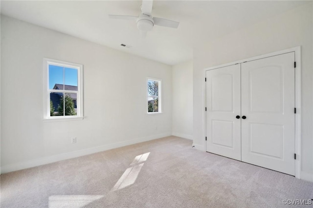 unfurnished bedroom with light colored carpet, ceiling fan, and a closet