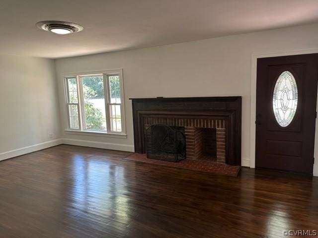 unfurnished living room with a brick fireplace and dark hardwood / wood-style floors