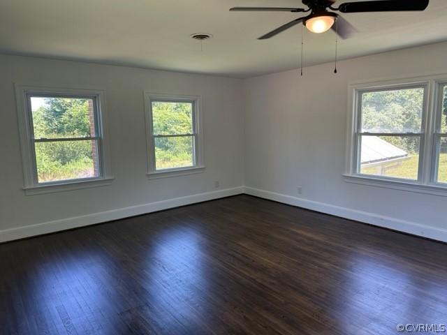 unfurnished room featuring ceiling fan, a wealth of natural light, and dark hardwood / wood-style floors