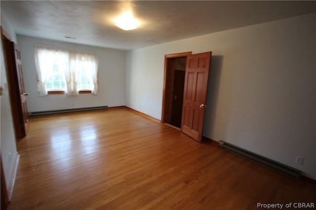 empty room featuring a baseboard radiator, baseboard heating, and wood finished floors