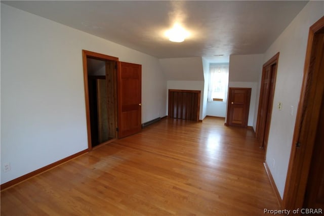 additional living space with light wood-style flooring and baseboards