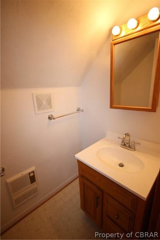 bathroom featuring lofted ceiling, visible vents, vanity, and heating unit