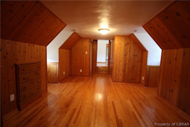 bonus room featuring lofted ceiling, wood walls, and light wood-style floors