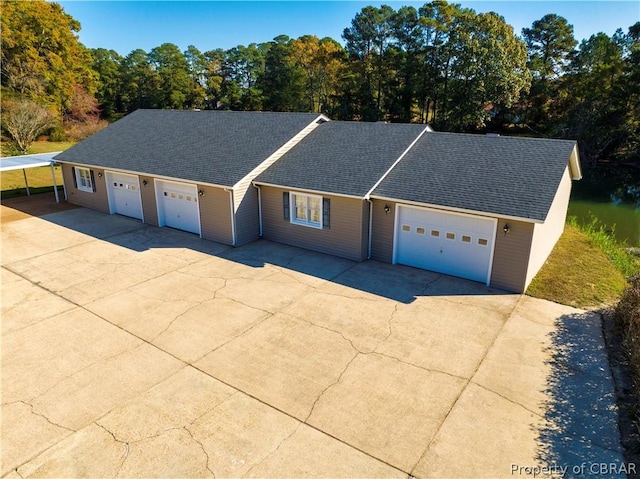 ranch-style house featuring a shingled roof, concrete driveway, and an attached garage