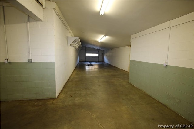 hall featuring concrete flooring and concrete block wall