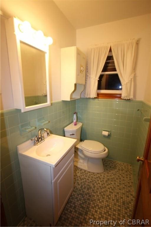 bathroom featuring a wainscoted wall, vanity, toilet, and tile walls