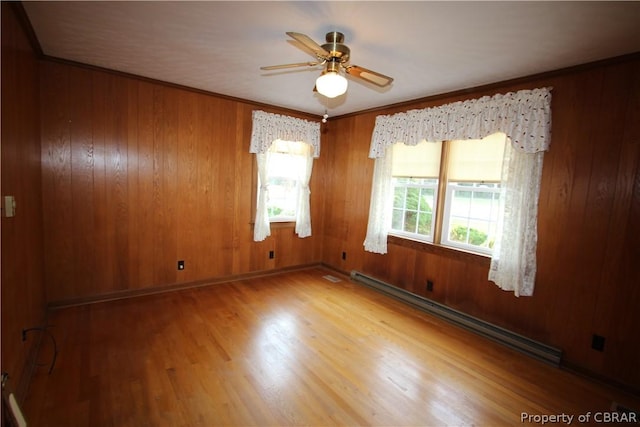 unfurnished room with a baseboard heating unit, ceiling fan, ornamental molding, and wood finished floors