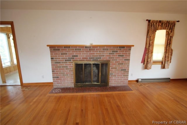 unfurnished living room with visible vents, baseboard heating, a brick fireplace, wood finished floors, and baseboards