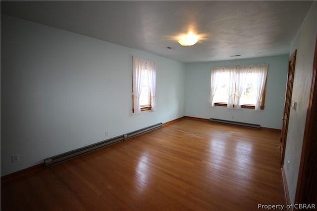 unfurnished room with a baseboard heating unit, a baseboard radiator, and wood finished floors