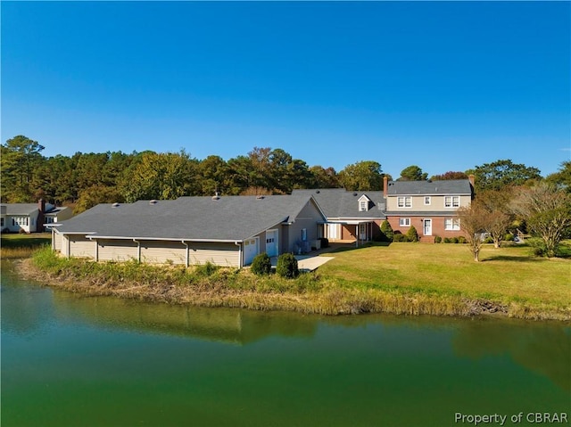 back of property featuring a garage, a lawn, and a water view