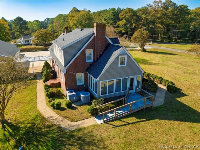 rear view of house with a chimney, central AC unit, fence, and a lawn