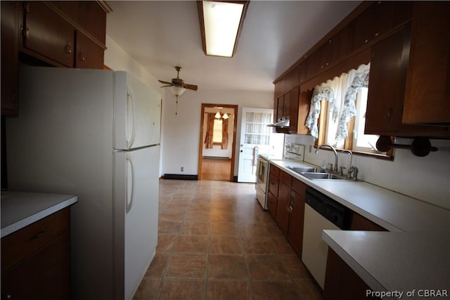 kitchen featuring light countertops, a ceiling fan, a sink, white appliances, and under cabinet range hood