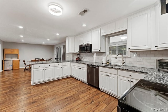 kitchen with light hardwood / wood-style floors, appliances with stainless steel finishes, tasteful backsplash, and white cabinets