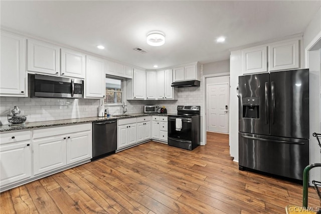 kitchen with black appliances, sink, backsplash, white cabinetry, and hardwood / wood-style flooring