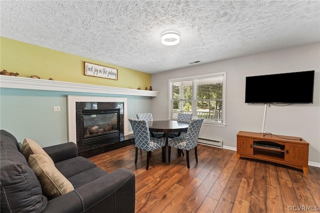 dining space featuring a baseboard heating unit, a textured ceiling, and dark hardwood / wood-style flooring