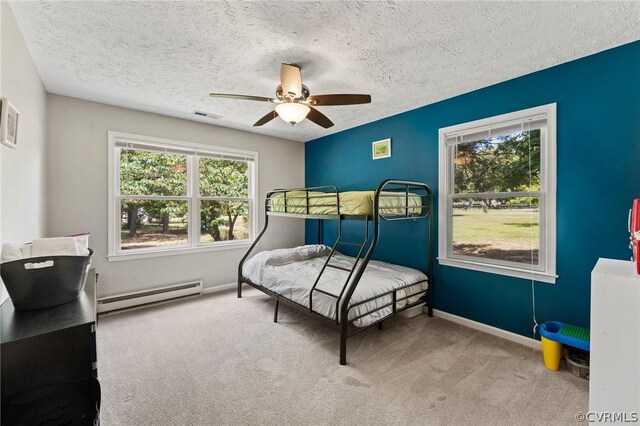 bedroom featuring baseboard heating, a textured ceiling, ceiling fan, and carpet floors