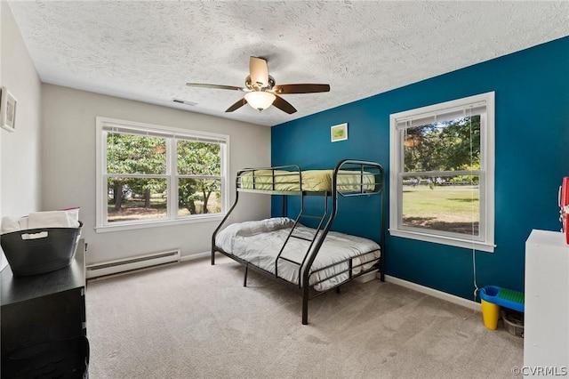 bedroom with a baseboard heating unit, light colored carpet, a textured ceiling, and ceiling fan