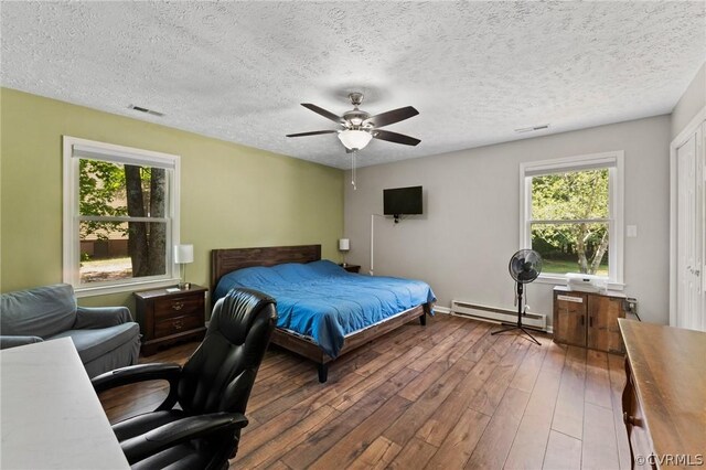 bedroom featuring a textured ceiling, a baseboard radiator, wood-type flooring, and ceiling fan