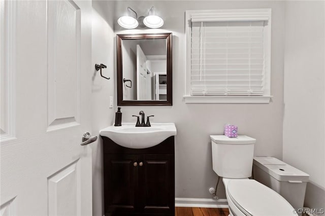 bathroom featuring vanity, wood-type flooring, and toilet