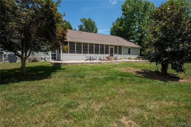 rear view of house with a sunroom, a patio area, and a lawn