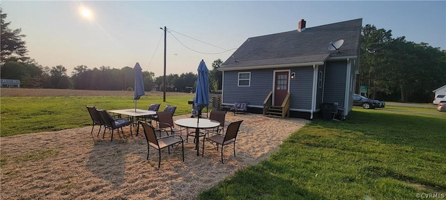 patio terrace at dusk featuring a lawn