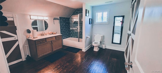 full bathroom with vanity, tiled shower / bath combo, vaulted ceiling, hardwood / wood-style floors, and toilet