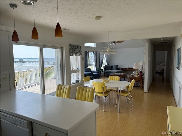 dining space featuring visible vents, light wood finished floors, and a textured ceiling