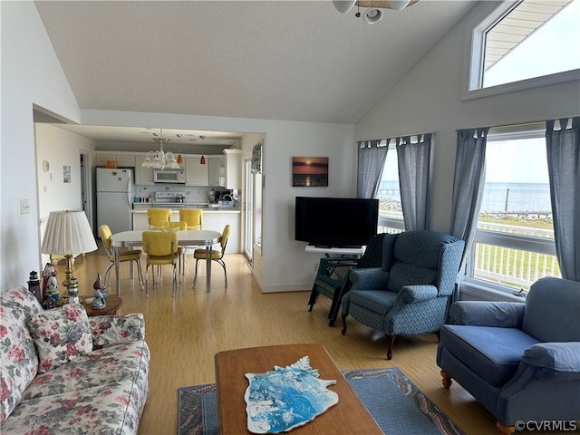 living room featuring high vaulted ceiling, light wood-style flooring, and a textured ceiling