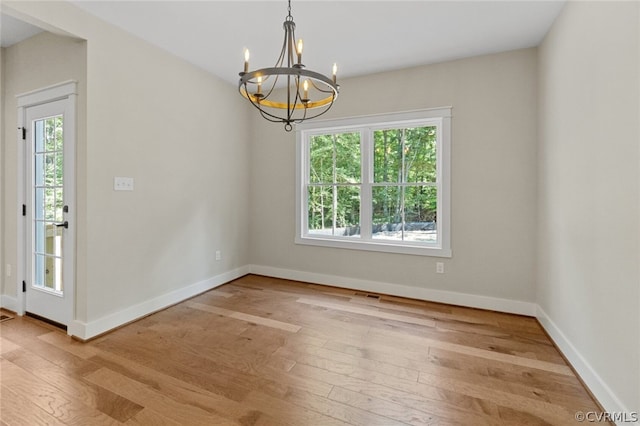 unfurnished dining area with a notable chandelier and light hardwood / wood-style flooring