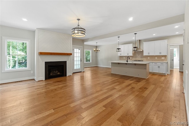 kitchen with light countertops, wall chimney range hood, open floor plan, and light wood-type flooring