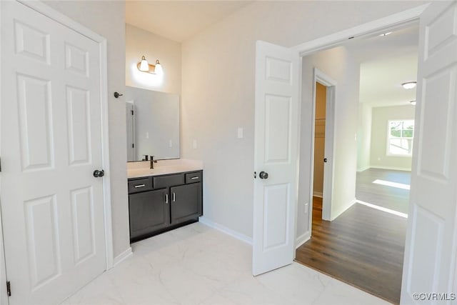 bathroom with baseboards, marble finish floor, and vanity