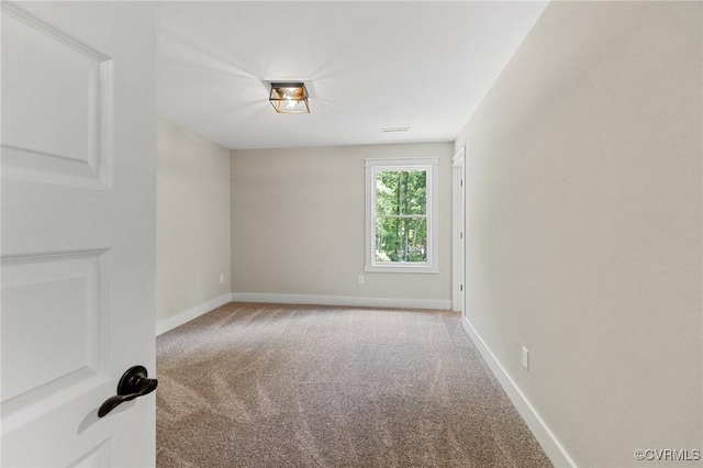 carpeted spare room with visible vents and baseboards