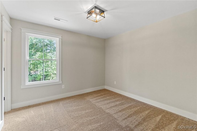 carpeted empty room featuring baseboards and visible vents