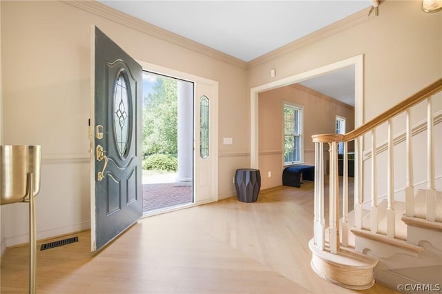 foyer with stairs, visible vents, plenty of natural light, and crown molding