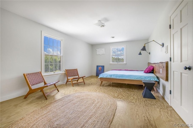 bedroom featuring multiple windows, baseboards, and wood finished floors