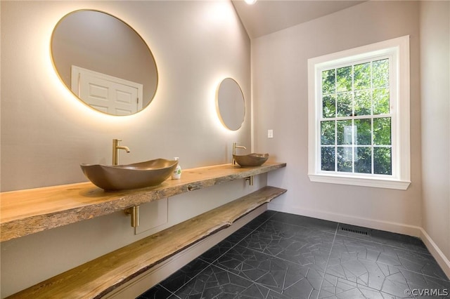 full bathroom with double vanity, visible vents, baseboards, and a sink
