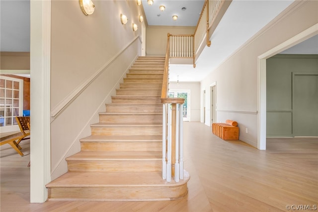 stairs with crown molding and light hardwood / wood-style flooring