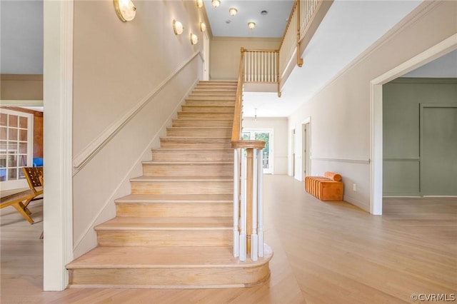 stairway with ornamental molding, a high ceiling, and wood finished floors