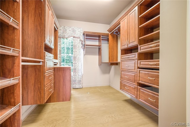 walk in closet with light hardwood / wood-style flooring