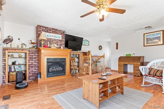 living room featuring ceiling fan, wood-type flooring, and a textured ceiling