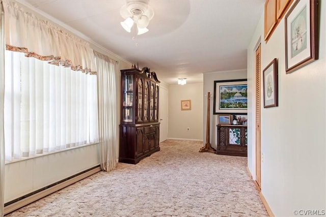 interior space with light colored carpet, baseboard heating, ornamental molding, and ceiling fan