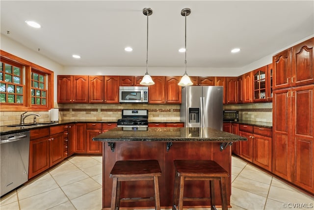 kitchen with appliances with stainless steel finishes, pendant lighting, decorative backsplash, and a kitchen island