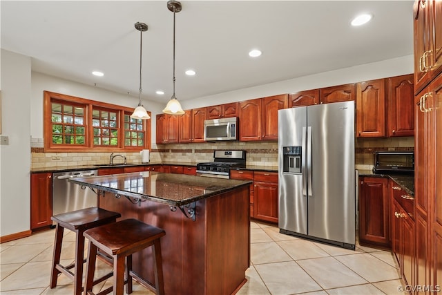 kitchen with decorative backsplash, hanging light fixtures, appliances with stainless steel finishes, and light tile patterned floors